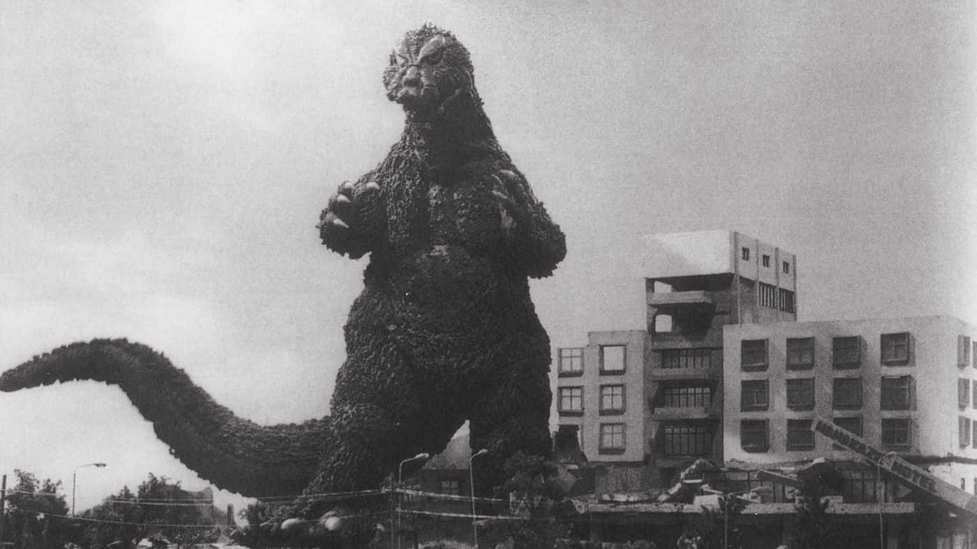 Godzilla 1954 桌布 壁紙 — 高聳的哥斯拉站在被摧毀的城市建築物中，形成戲劇性的黑白場景。