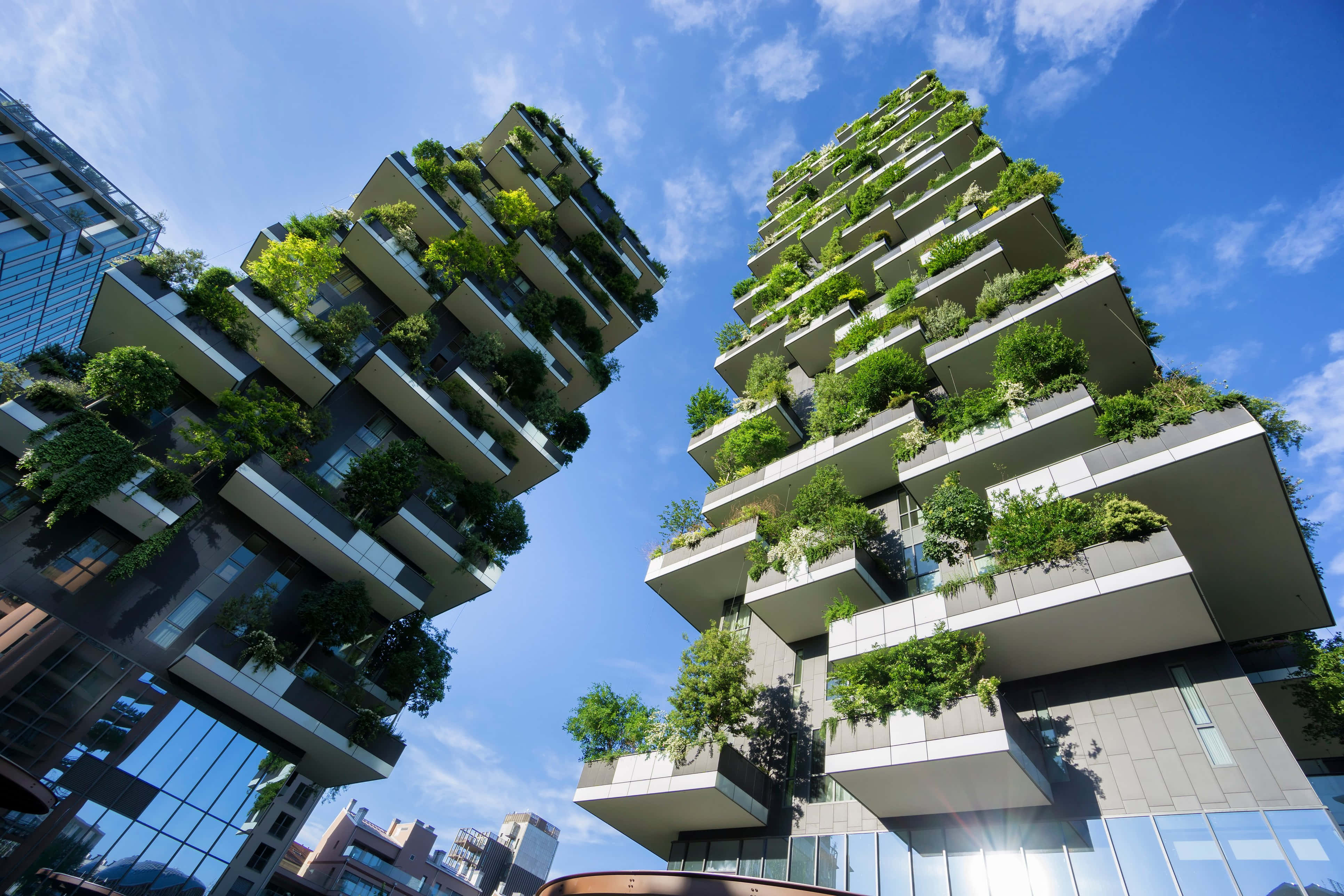 Green Buildings 桌布 壁紙 — 高聳的垂直花園沿著現代摩天大樓層層疊落，背景是晴朗的藍天和蓬鬆的白雲。