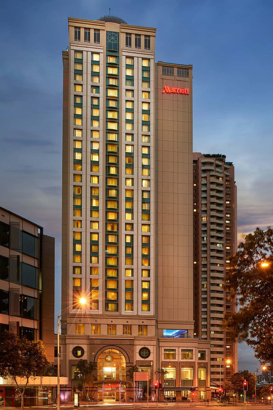 Hotel 桌布 壁紙 — 高聳的萬豪酒店大樓在暮色天空中散發溫暖燈光，融入城市景觀。