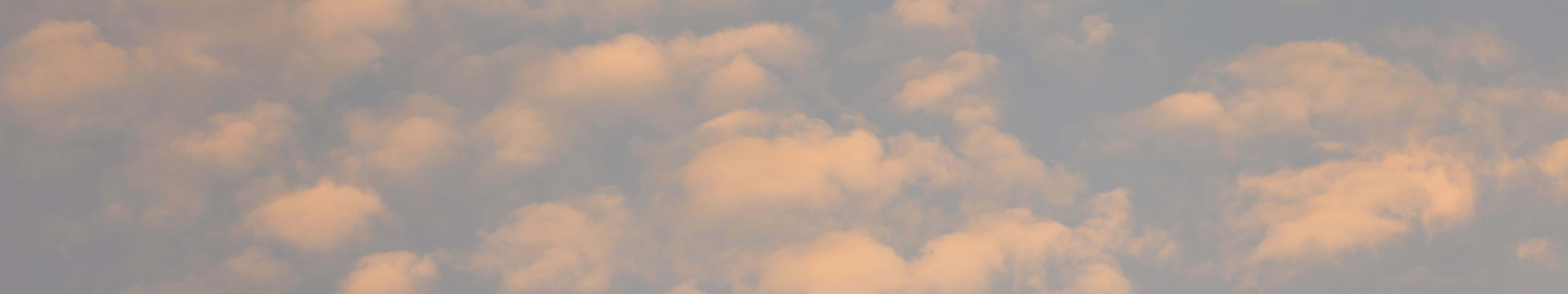 黃昏時分，金色雲朵在柔和的藍色天空中飄移。