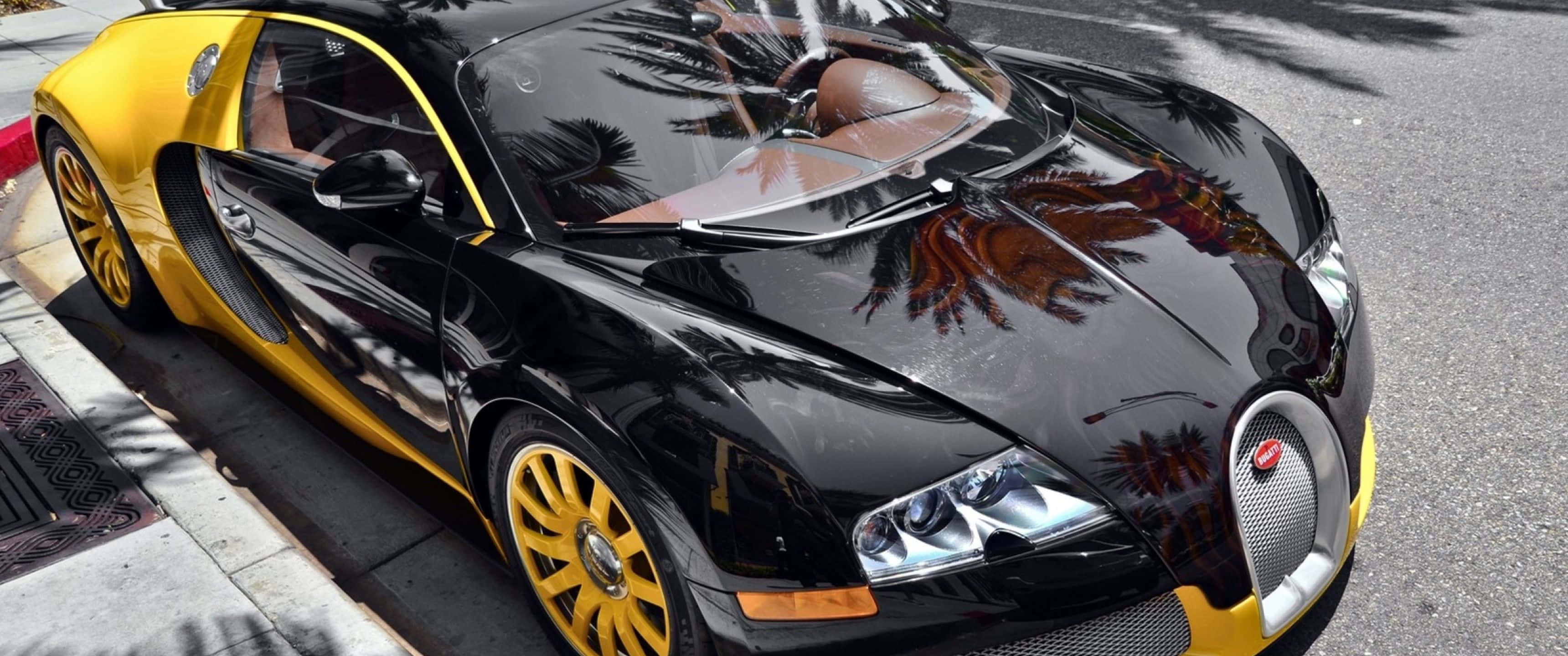 高解析度 Bugatti Chiron，視覺震撼 壁紙 — 一輛光澤的黑色和黃色Bugatti Veyron停放在陽光明媚的街道上，拋光的引擎蓋反射出棕櫚樹。