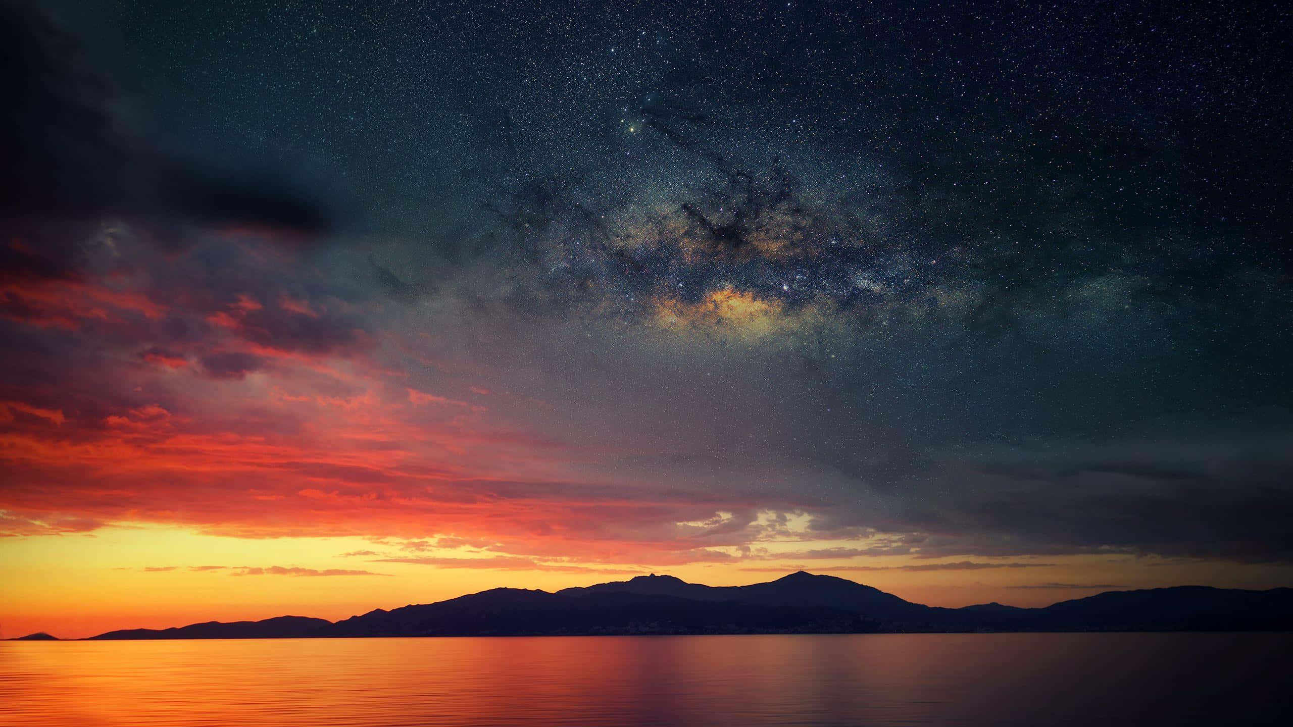 暮色中山脈和水面上方有銀河的星空