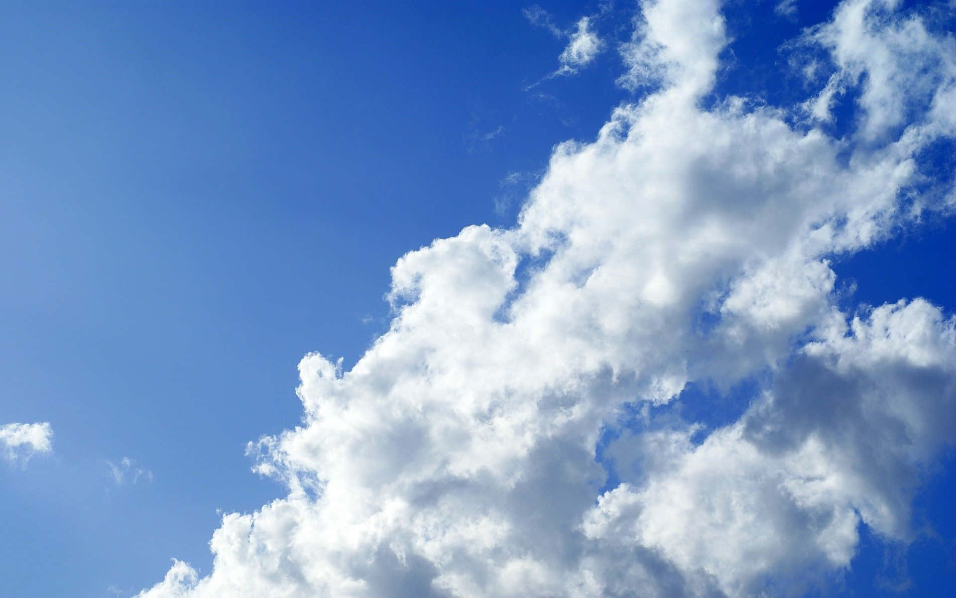 高解析度天空桌面背景 壁紙 — 廣闊藍天，滿佈蓬鬆白雲，在地平線上飄移。