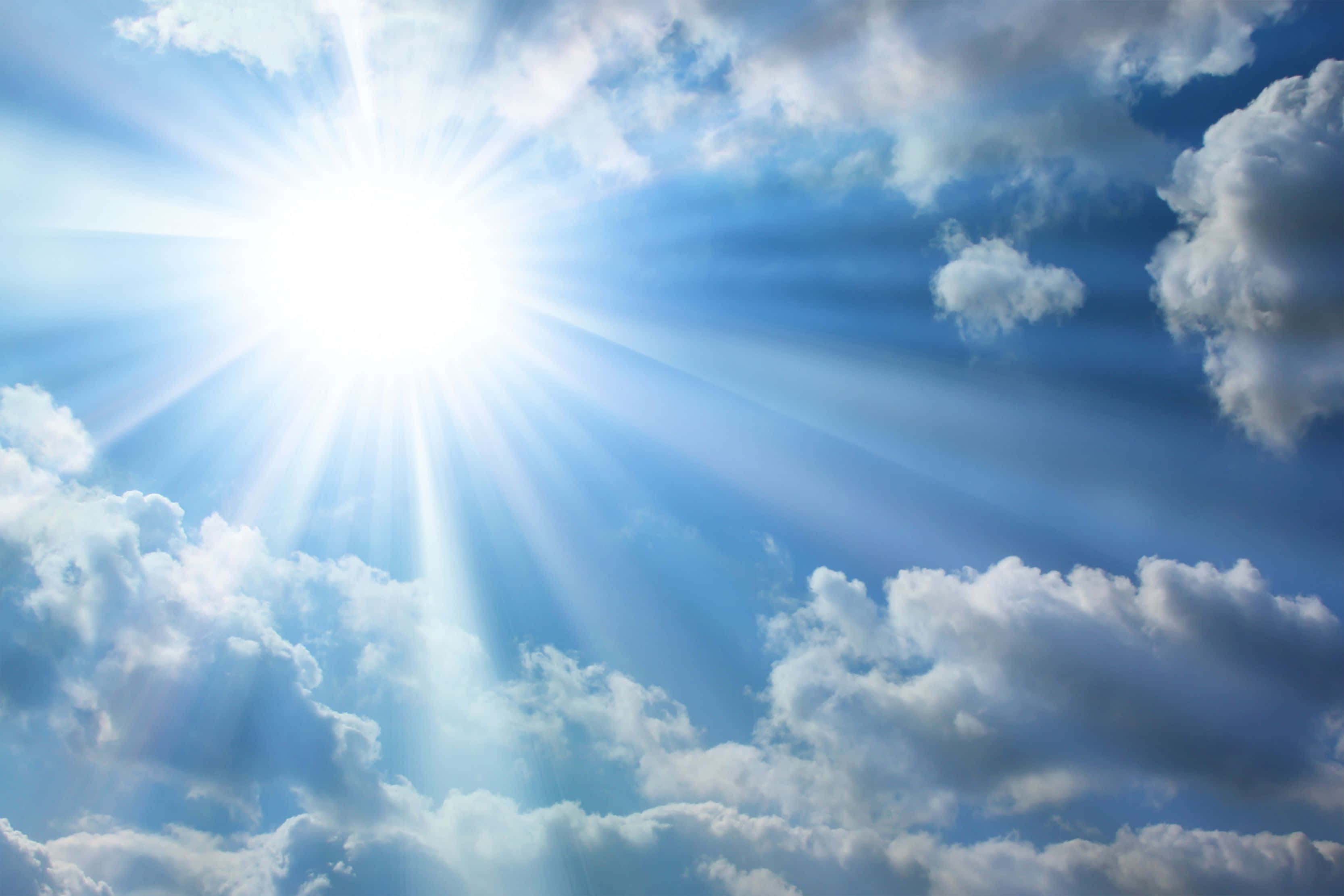 高解析度天空與明亮陽光 壁紙 — 一道燦爛的陽光穿透蓬鬆的白雲，映襯著充滿活力的藍天。