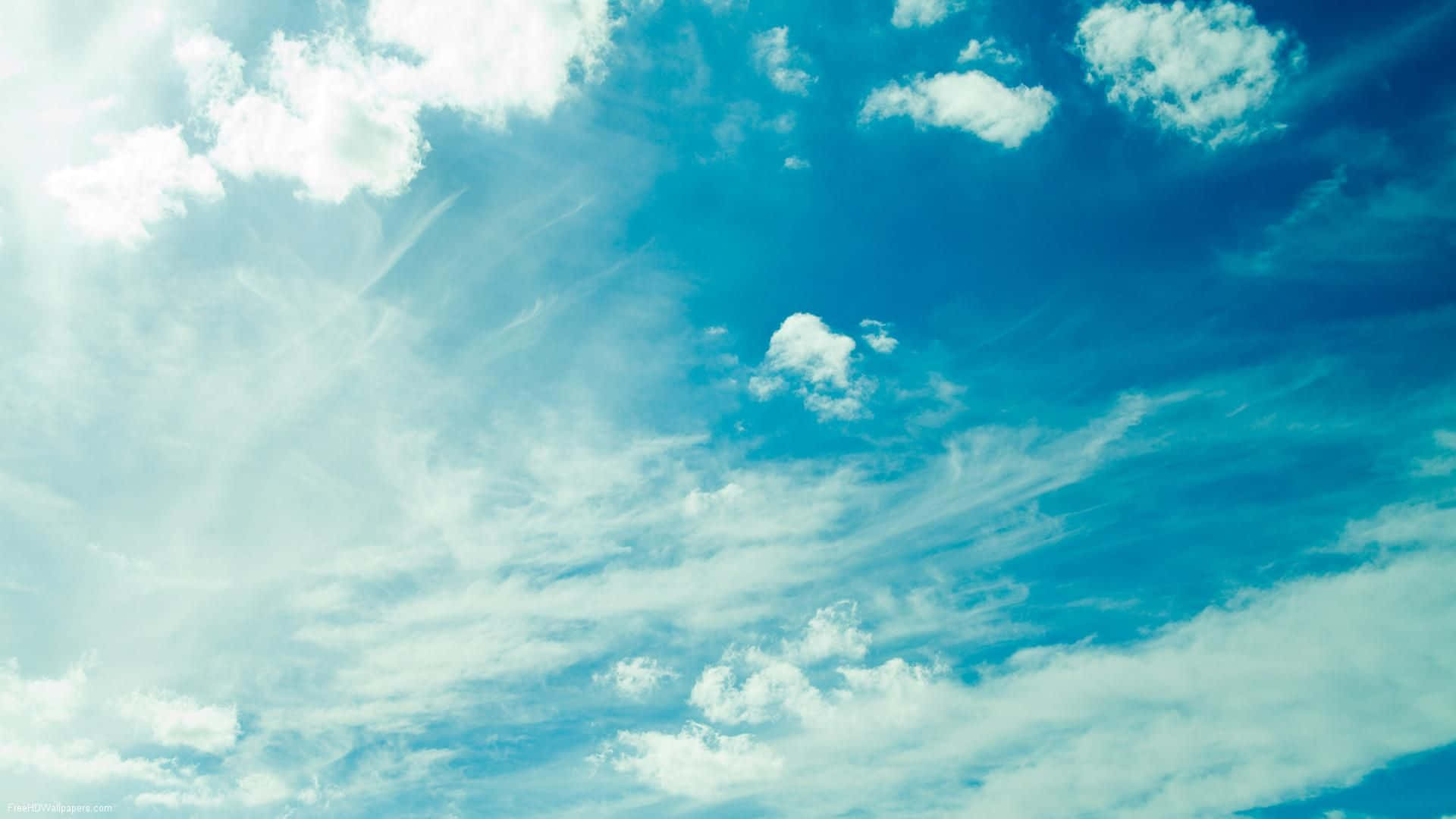 高解析度寶藍天空與白雲 壁紙 — 充滿活力的藍天，佈滿縷縷白雲和明亮的陽光穿透而過。