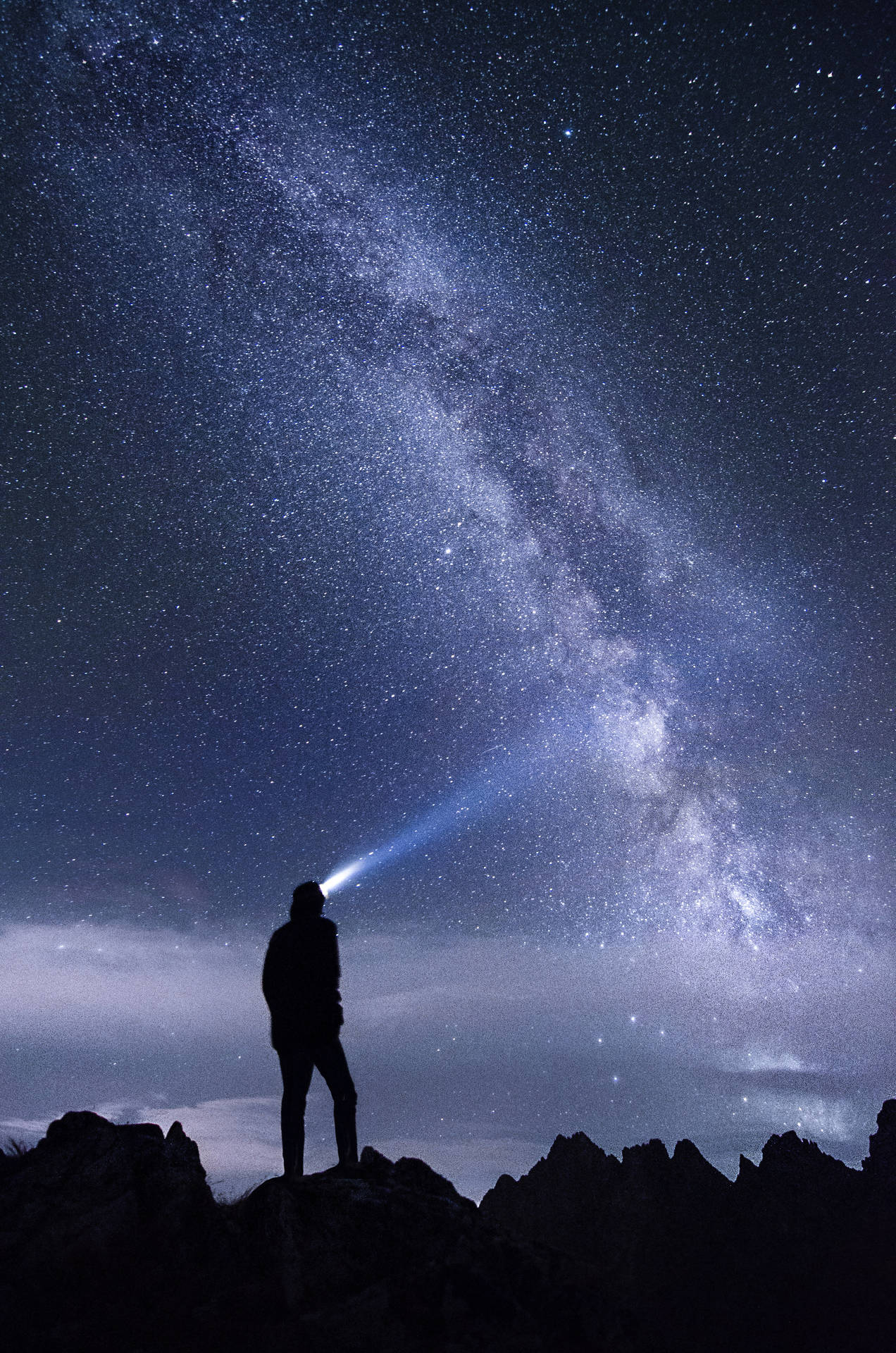 人在山頂上將手電筒照向星空
