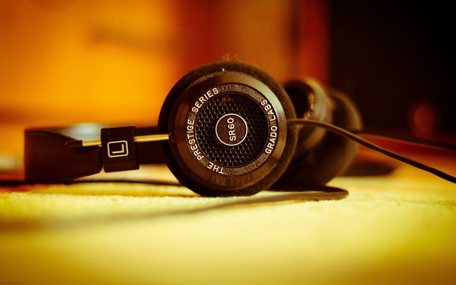 高解析度耳機壁紙 壁紙 — 黑色Grado SR60耳機特寫，放在柔軟的黃色表面上，溫暖的金色燈光下。