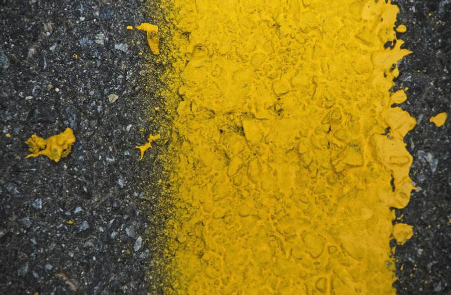 高解析度道路塗漆紋理 壁紙 — 鮮黃色的油漆潑灑與深色瀝青在粗糙的特寫紋理中形成鮮明對比。