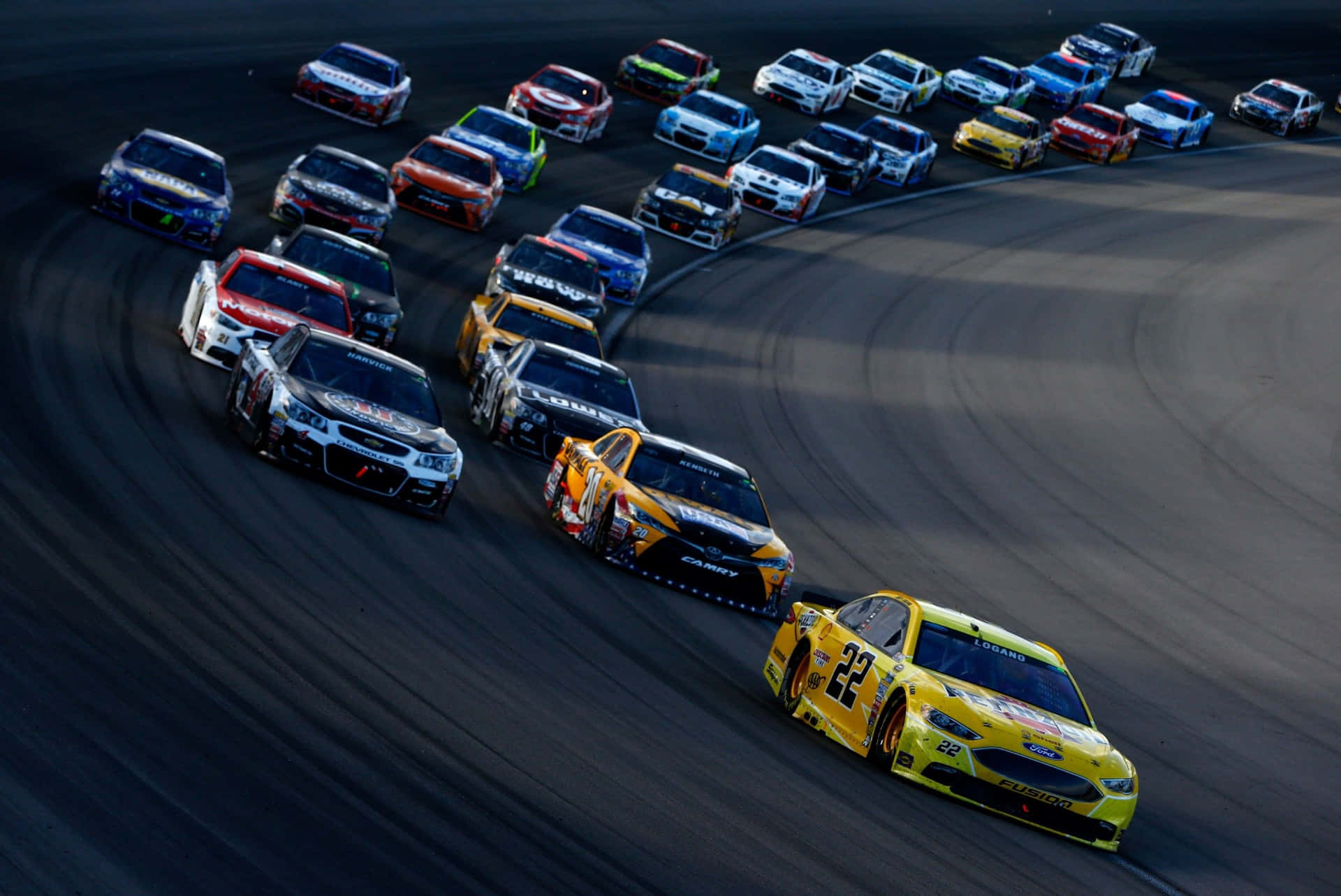 NASCAR賽車在日落時分沿彎曲賽道飛馳。