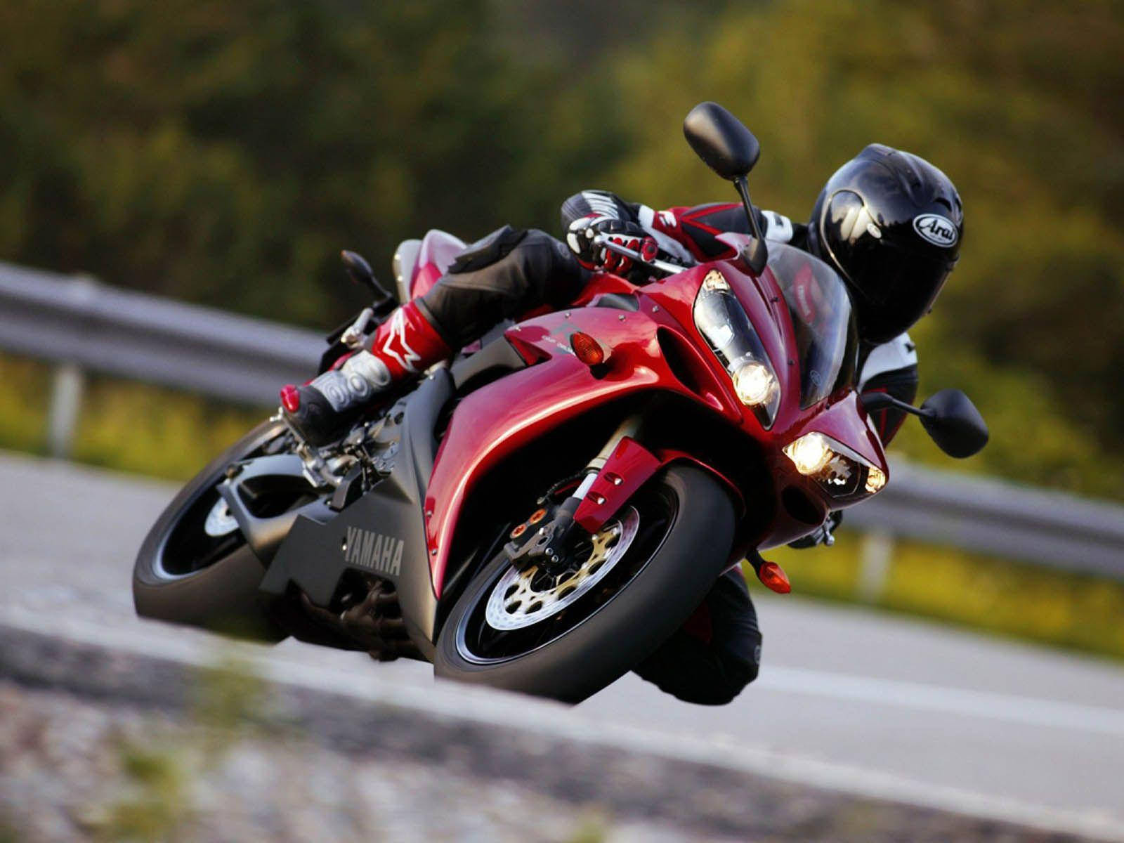 紅色Yamaha電單車在道路上轉彎傾斜，背景有綠色樹木。