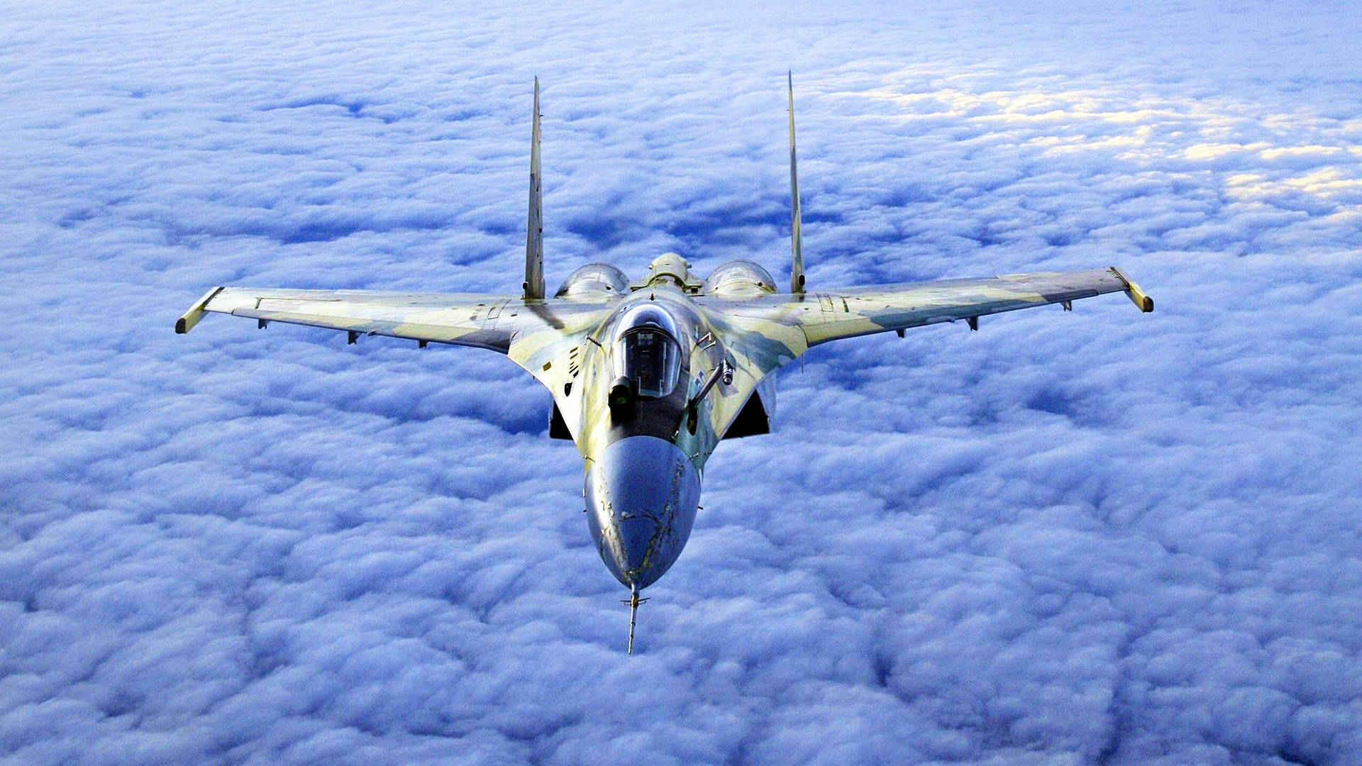 高速科技戰鬥機 壁紙 — 一架戰鬥機在晴朗的天空中翱翔於廣闊的蓬鬆藍色雲海之上。