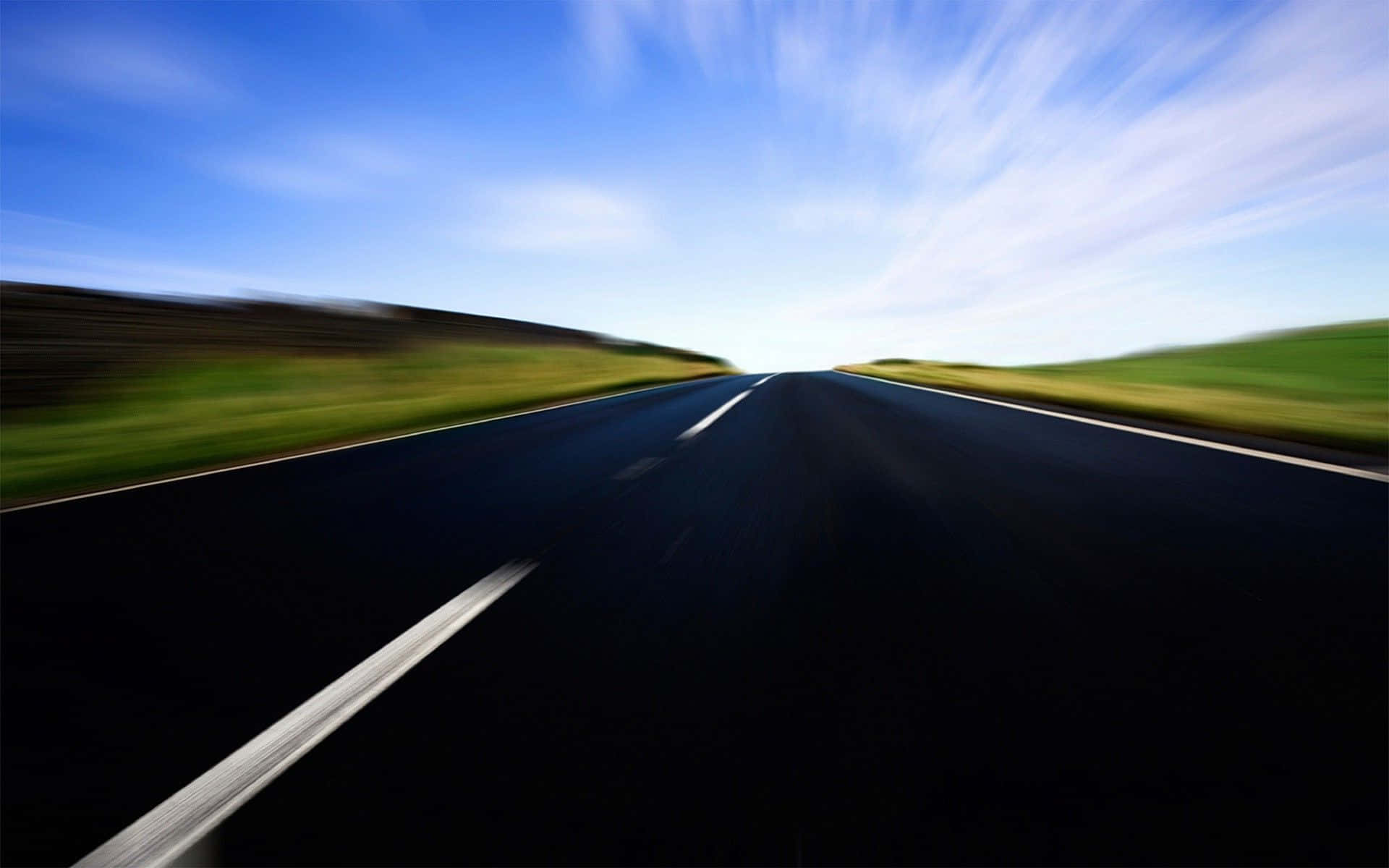 Motion Blur 桌布 壁紙 — 高速運動模糊視角，沿著一條筆直的瀝青路，兩旁是綠色的山丘，上方是明亮的藍天。