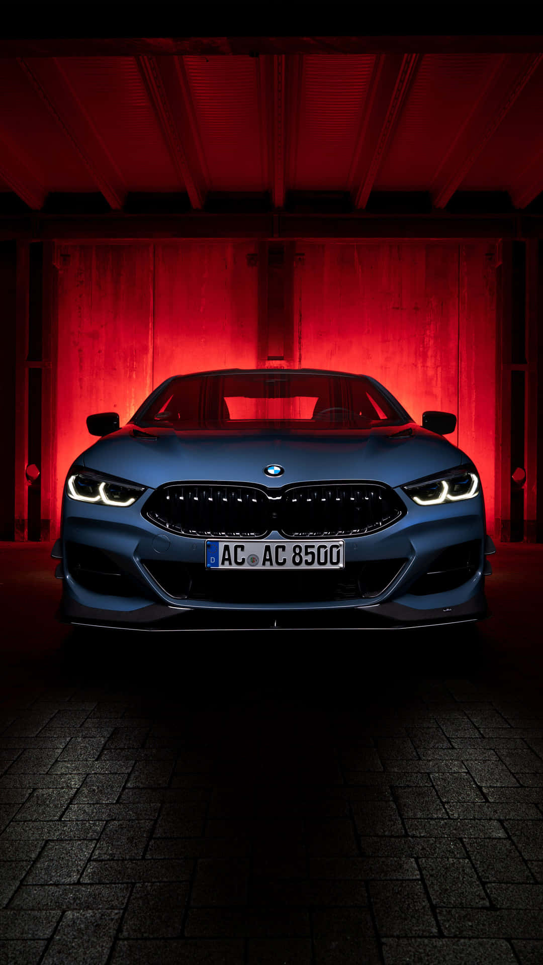 藍色BMW汽車在昏暗車庫中被紅燈照亮。
