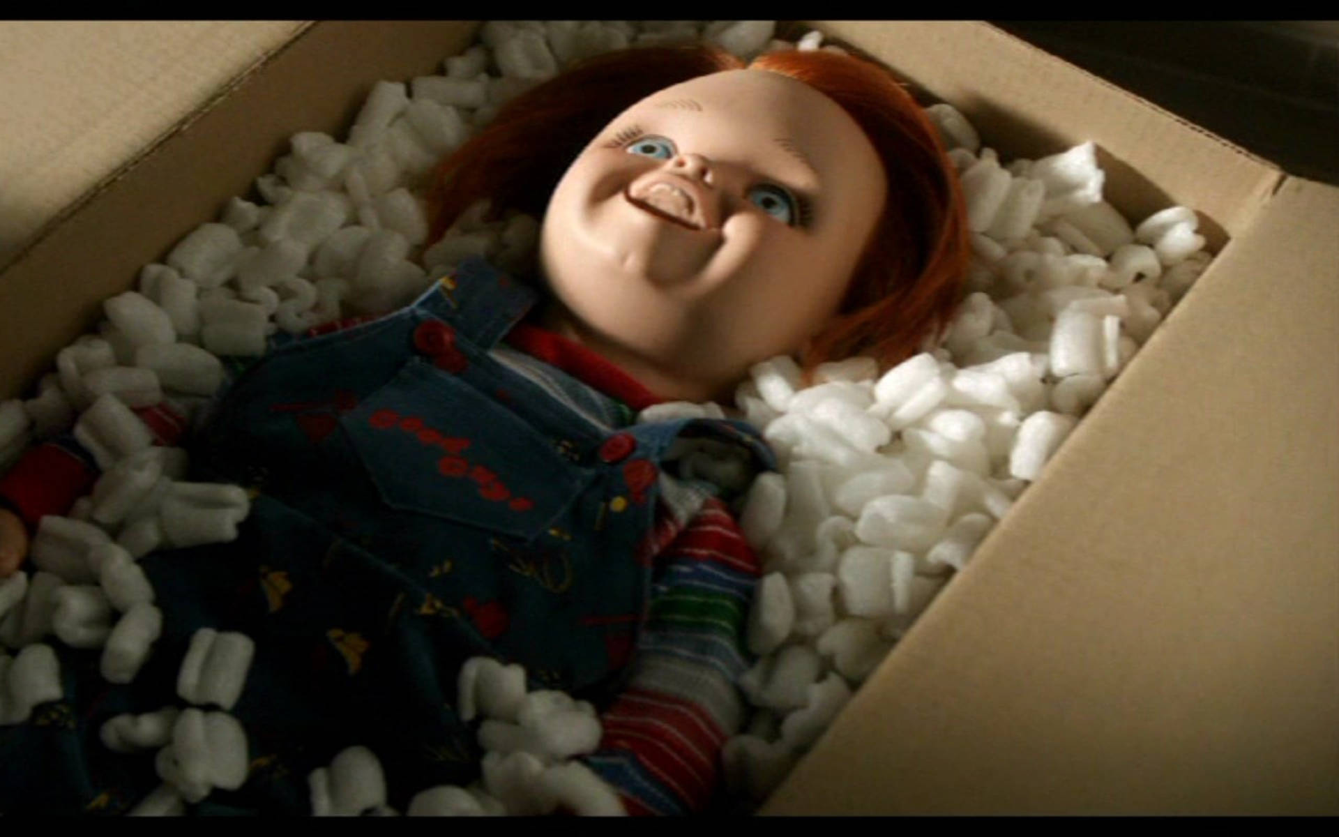 一個紅髮藍眼的恐怖娃娃在裝滿包裝花生的盒子裡。