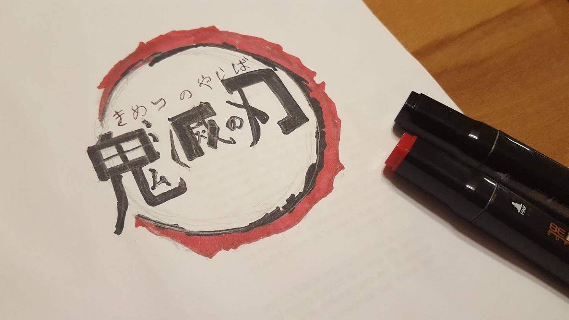 《鬼滅之刃》標誌藝術作品 壁紙 — 木質表面上嘅白紙上，黑色同紅色標記旁邊，手繪日本漢字標誌同紅色墨水圓圈。