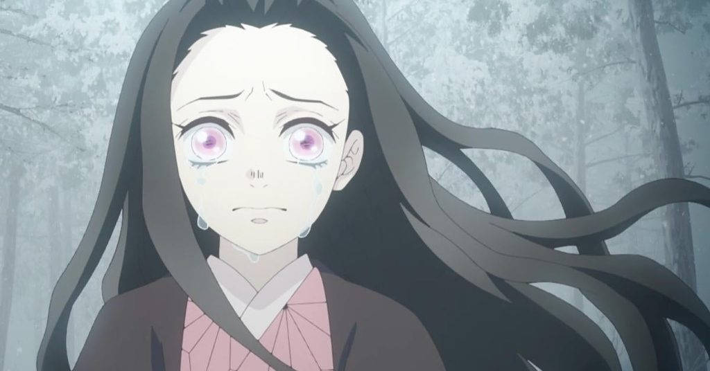 鬼滅之刃 祢豆子 悲傷畫面 壁紙 — 一個淚流滿面的動漫女孩，長長的黑髮和粉紅色的眼睛，站在迷霧森林中，穿著粉紅色和棕色的和服。