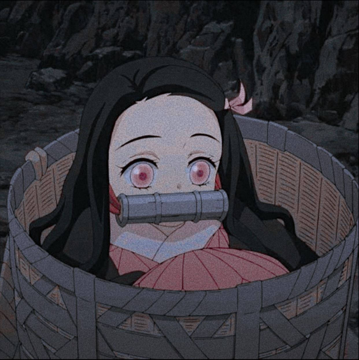 鬼滅之刃 露比可愛眼眸 壁紙 — 一位年輕的動漫女孩，粉紅色眼睛，黑色頭髮，坐在一個編織籃子裡，用金屬管塞住嘴巴，背景是黑暗的岩石。