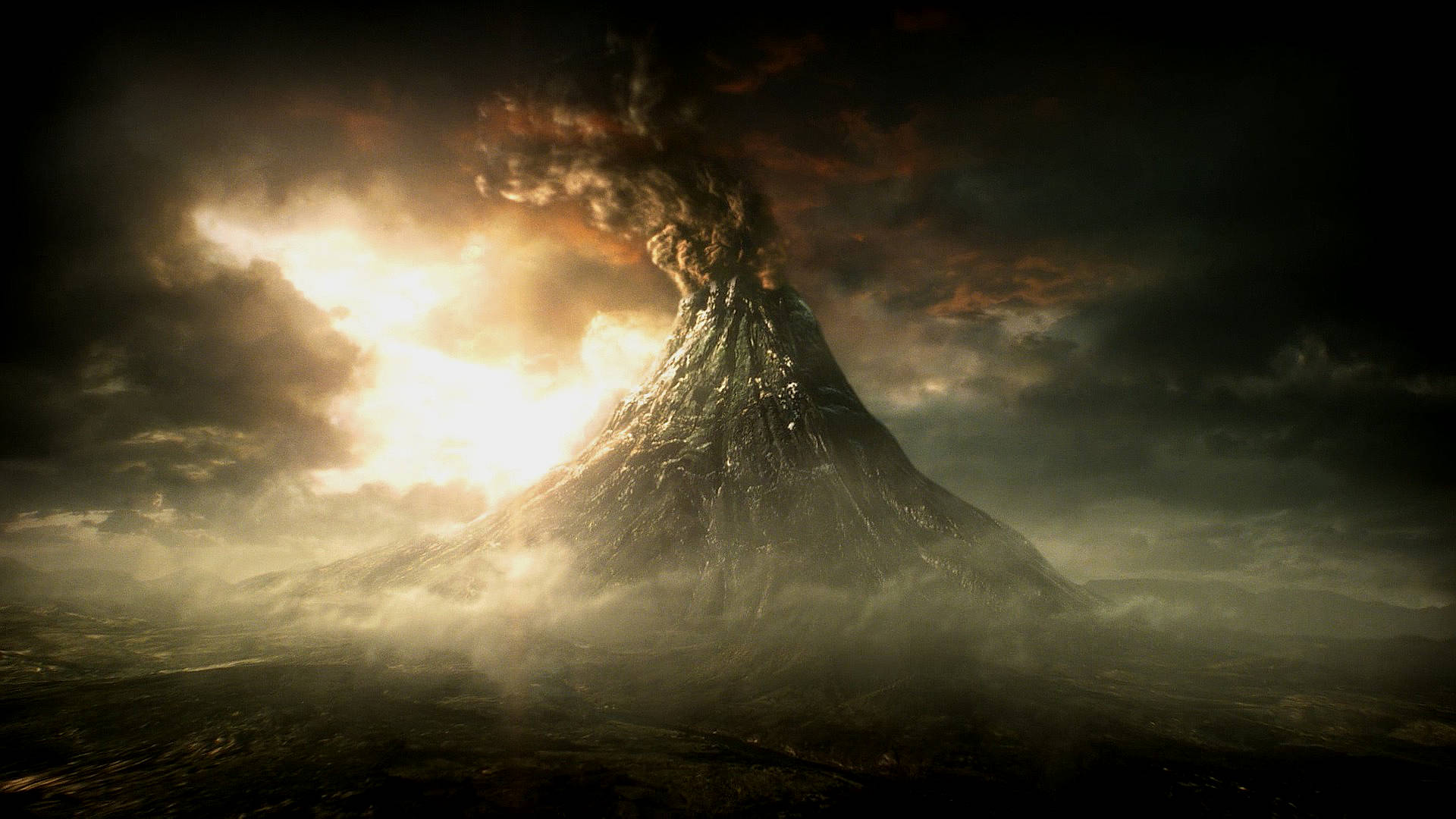 魔多陰影火山爆發 壁紙 — 一座高聳的火山在戲劇性的日落天空背景下噴發熾熱的熔岩和煙霧。