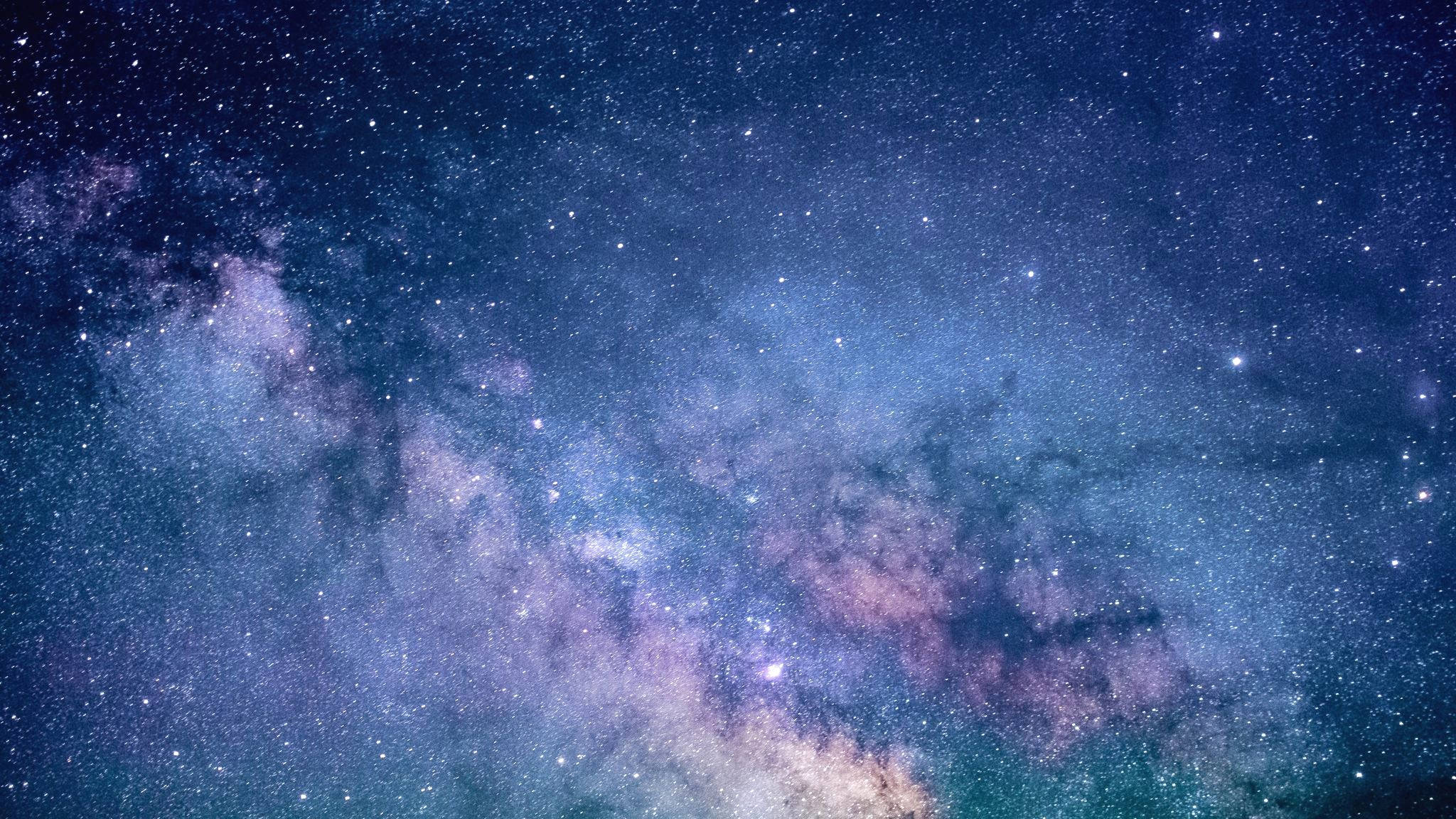 魔法星塵星系 壁紙 — 令人嘆為觀止的銀河系景觀，在繁星點點的夜空下散發出充滿活力的紫色和藍色光芒。