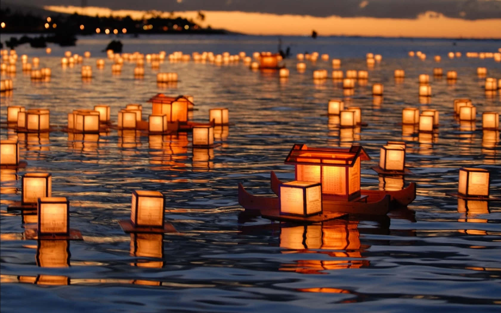 數百盞發光的燈籠在日落時分漂浮在平靜的水面上。