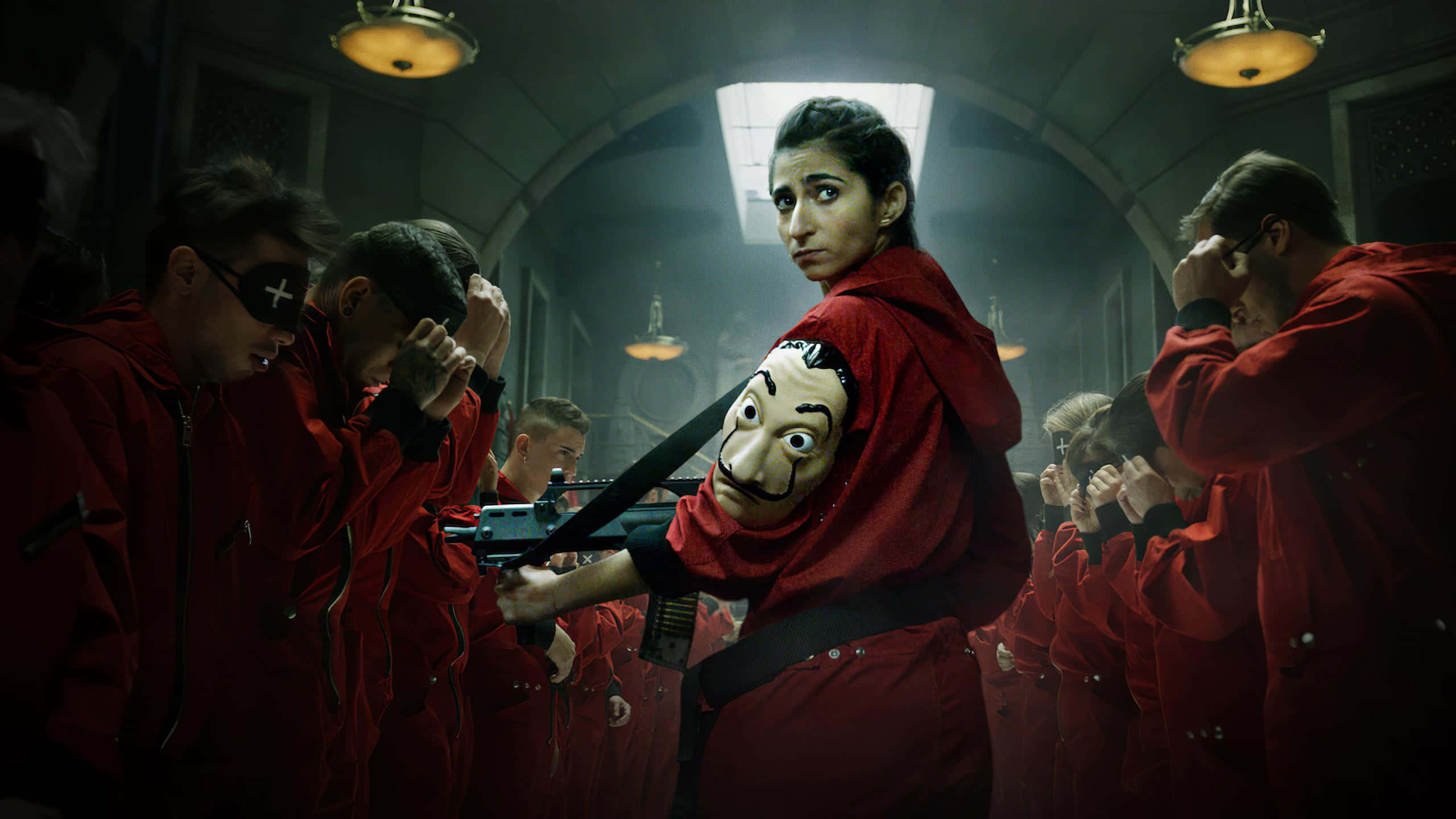Money Heist 桌布 壁紙 — 《魷魚遊戲》中緊張的一幕，一名身穿紅色連身衣的玩家手持步槍，而其他身穿紅色西裝的人在昏暗的房間裡遮住眼睛。