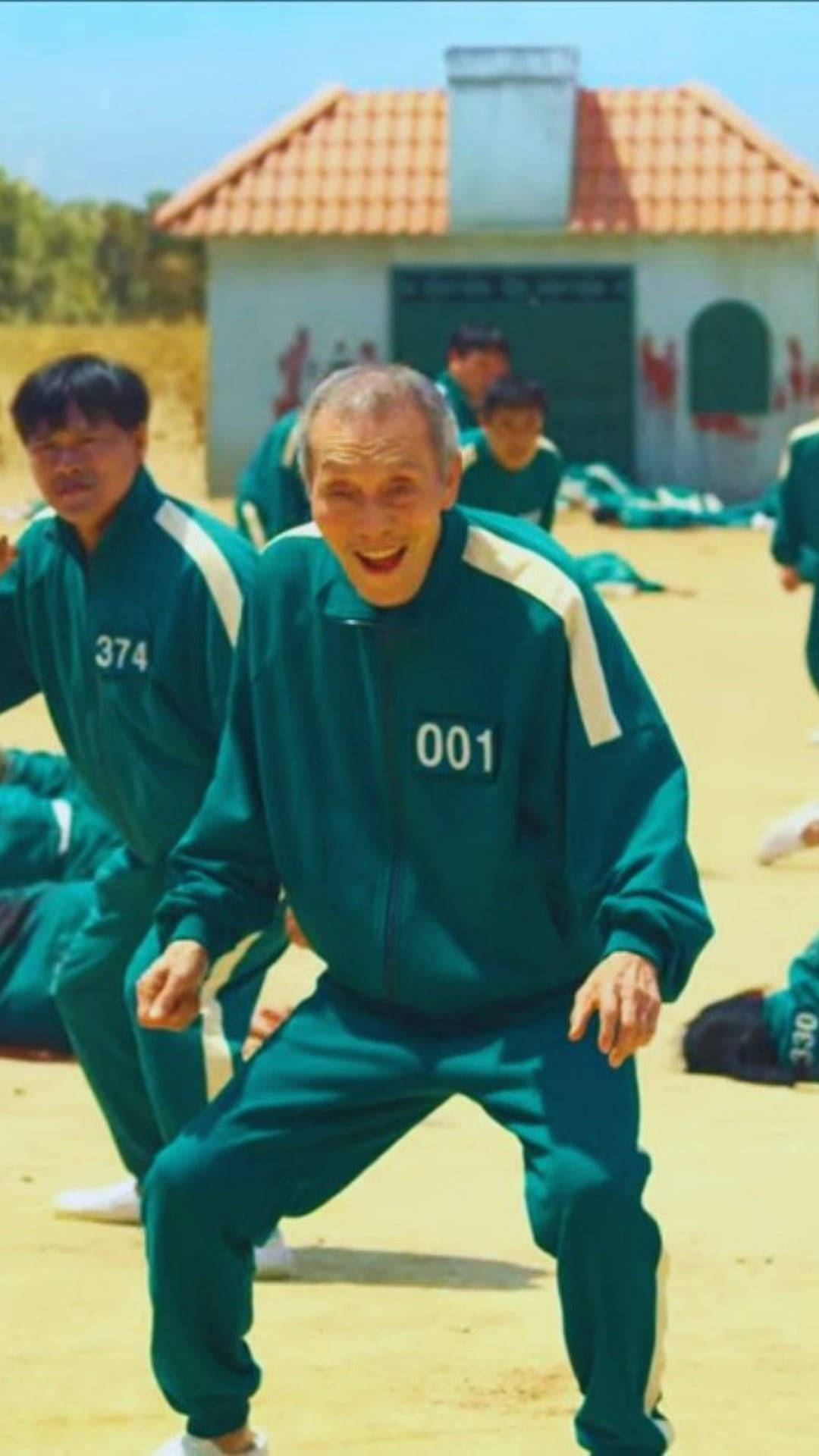 一位身穿綠色號碼運動服的長者在遊戲節目場景中與其他參賽者一起大笑。