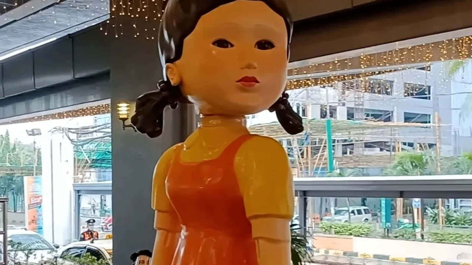 建築工地附近建築物內，穿著橙色連衣裙的女孩的光澤雕像。