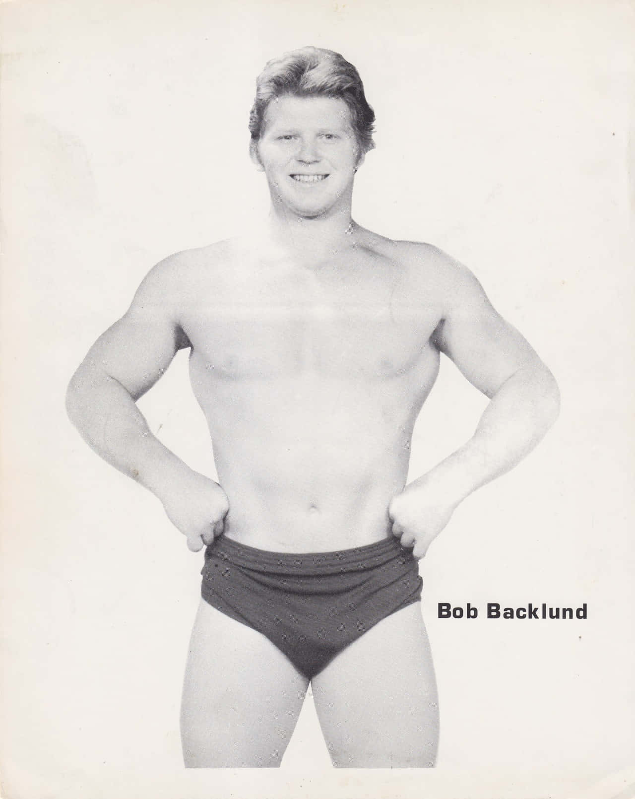 摔角手 Bob Backlund 穿著短褲，在復古照片中雙手叉腰擺姿勢。