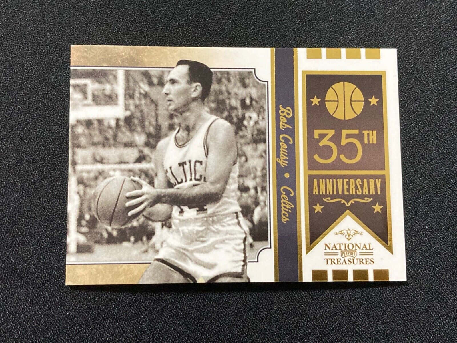 鮑勃·庫西塞爾提克隊35週年紀念海報 壁紙 — 復古籃球卡， featuring Bob Cousy 身穿塞爾特人隊服，手持籃球，背景為深色紋理。