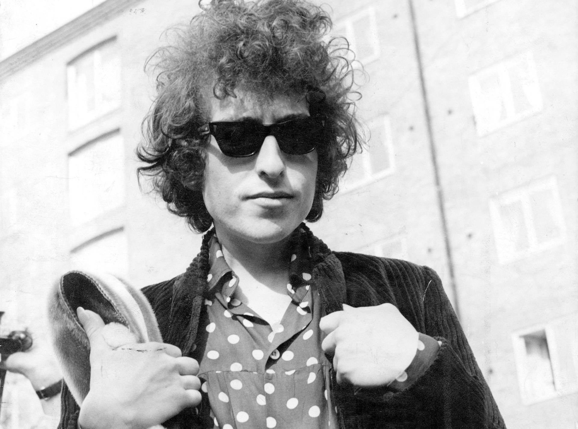 Bob Dylan 戴太陽眼鏡手持帽子在戶外