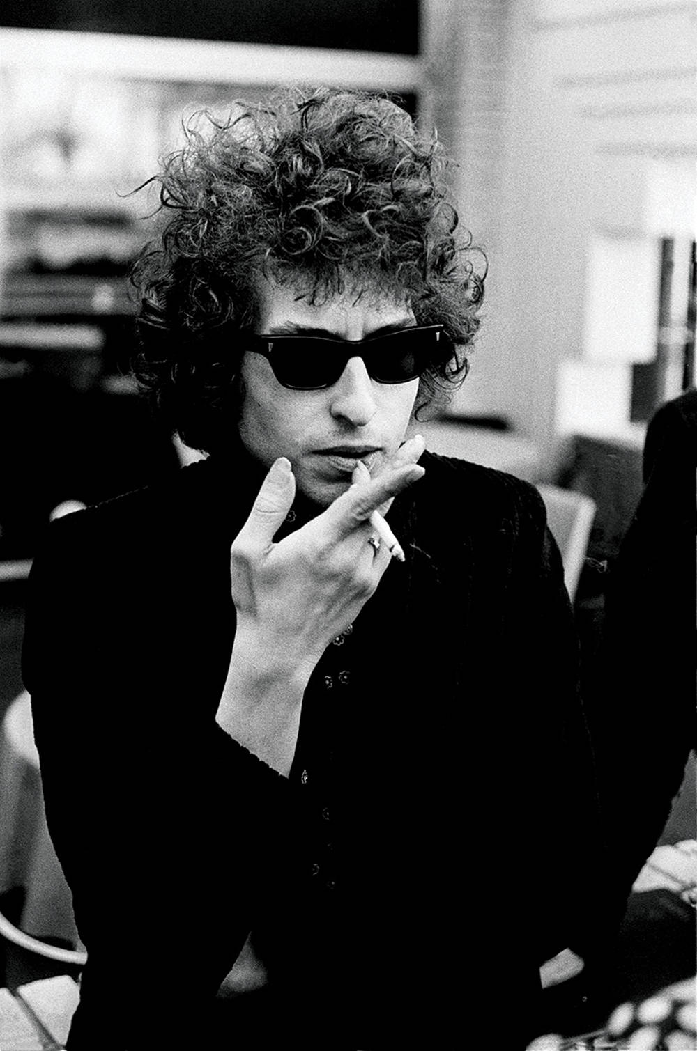 Bob Dylan 戴住太陽眼鏡喺黑白相入面食煙。