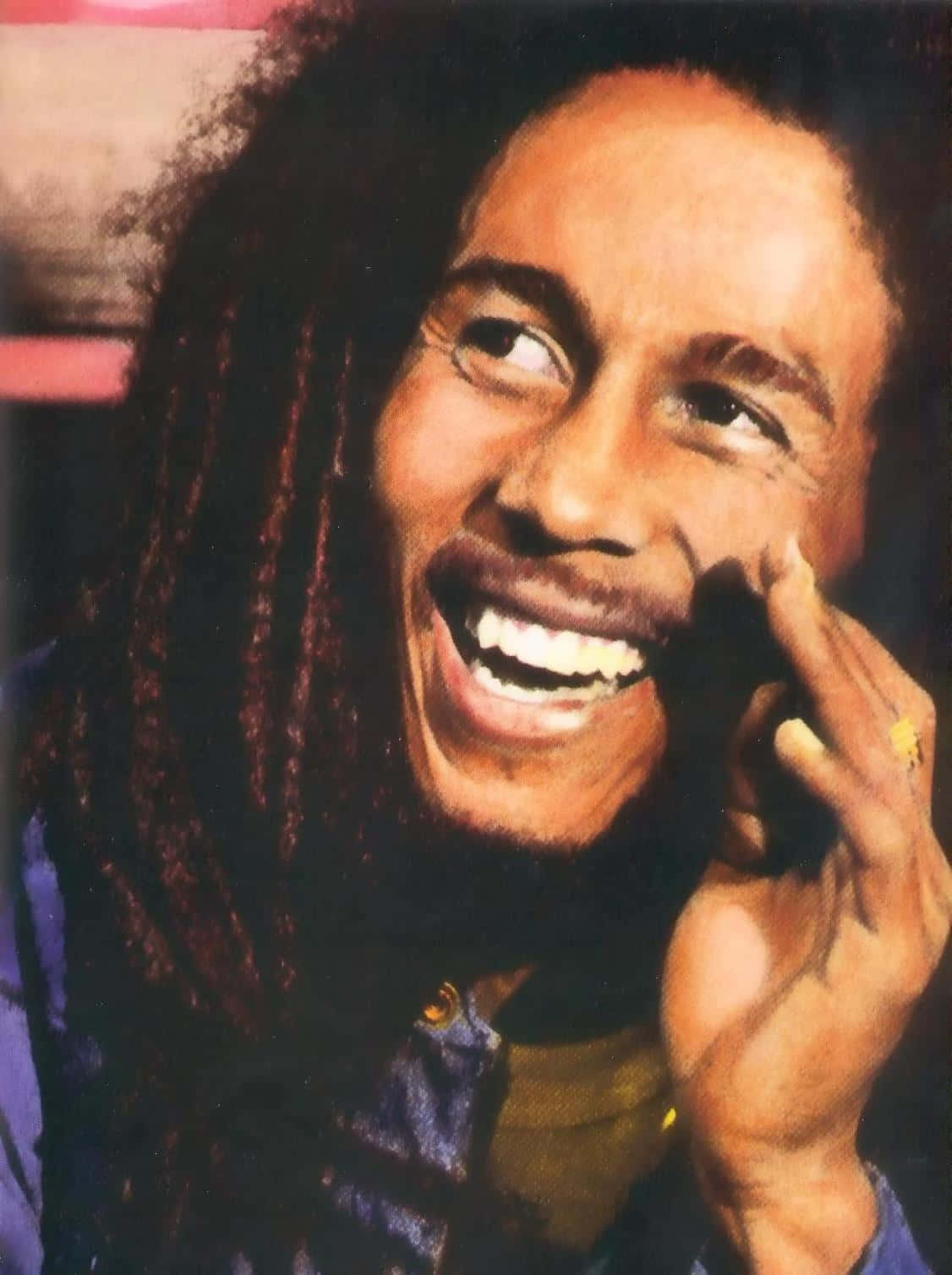 鮑勃·馬利——愛、和平與靈性的象徵 壁紙 — Bob Marley 愉快地大笑，手靠近臉龐，他的辮子在溫暖燈光下襯托出燦爛的笑容。