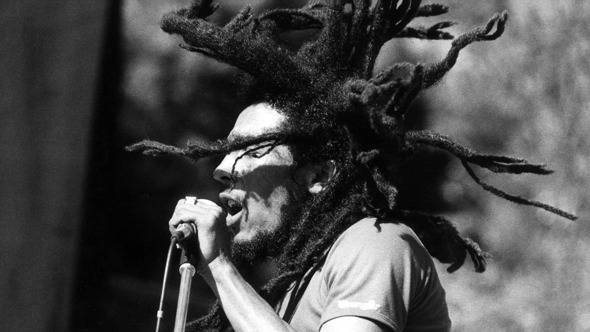 Bob Marley 留著長髮辮對著咪高峰唱歌的黑白照片。