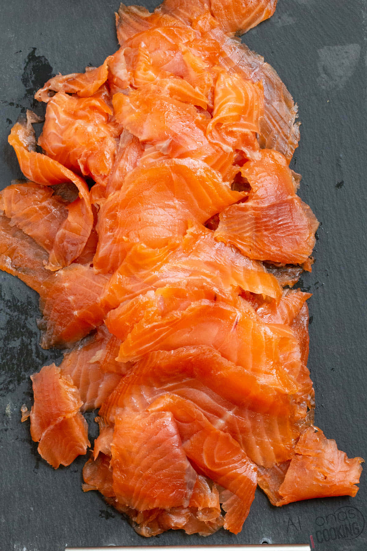 Salmon 桌布 壁紙 — 鮮橙色煙三文魚薄片堆疊在深色石板表面上。