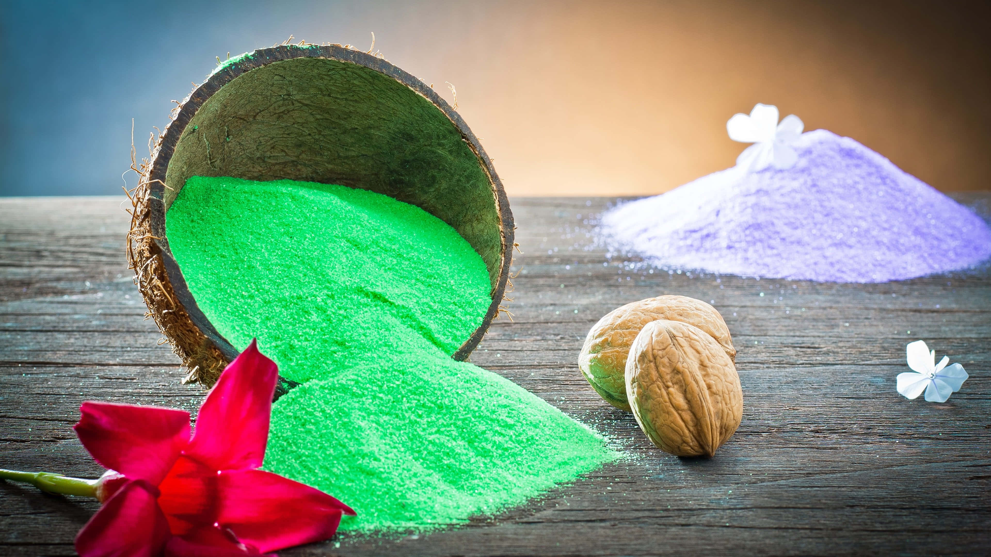 Aromatherapy 桌布 壁紙 — 鮮綠色粉末從椰子殼中灑出，旁邊有核桃和一朵紅花，放在質樸的木質表面上。