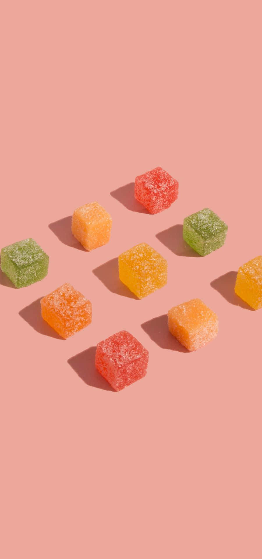 粉紅色背景上的彩色軟糖方塊。