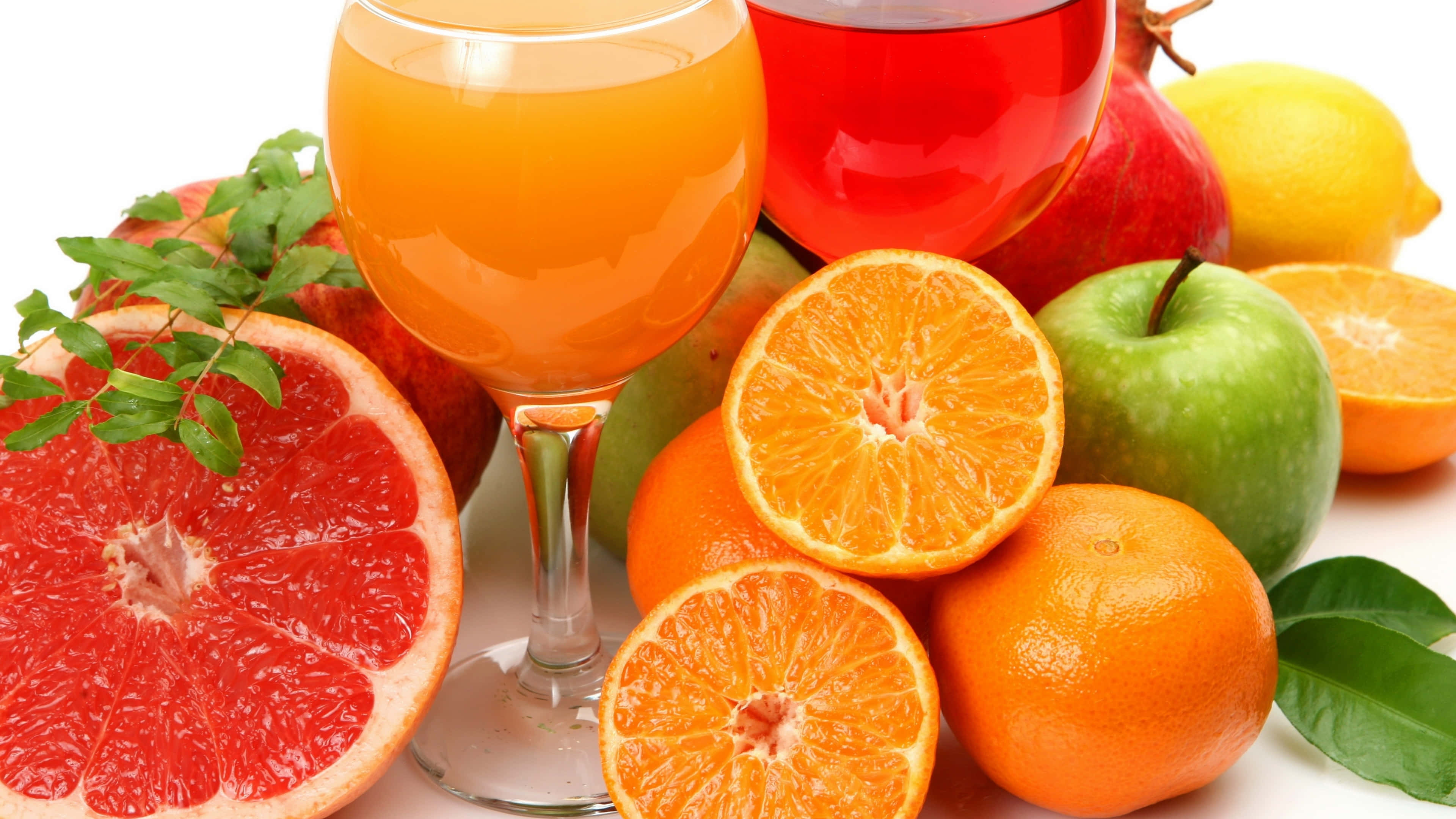 Food And Beverage 桌布 壁紙 — 鮮豔的柑橘類水果和果汁排列在白色背景上，搭配新鮮葉子。