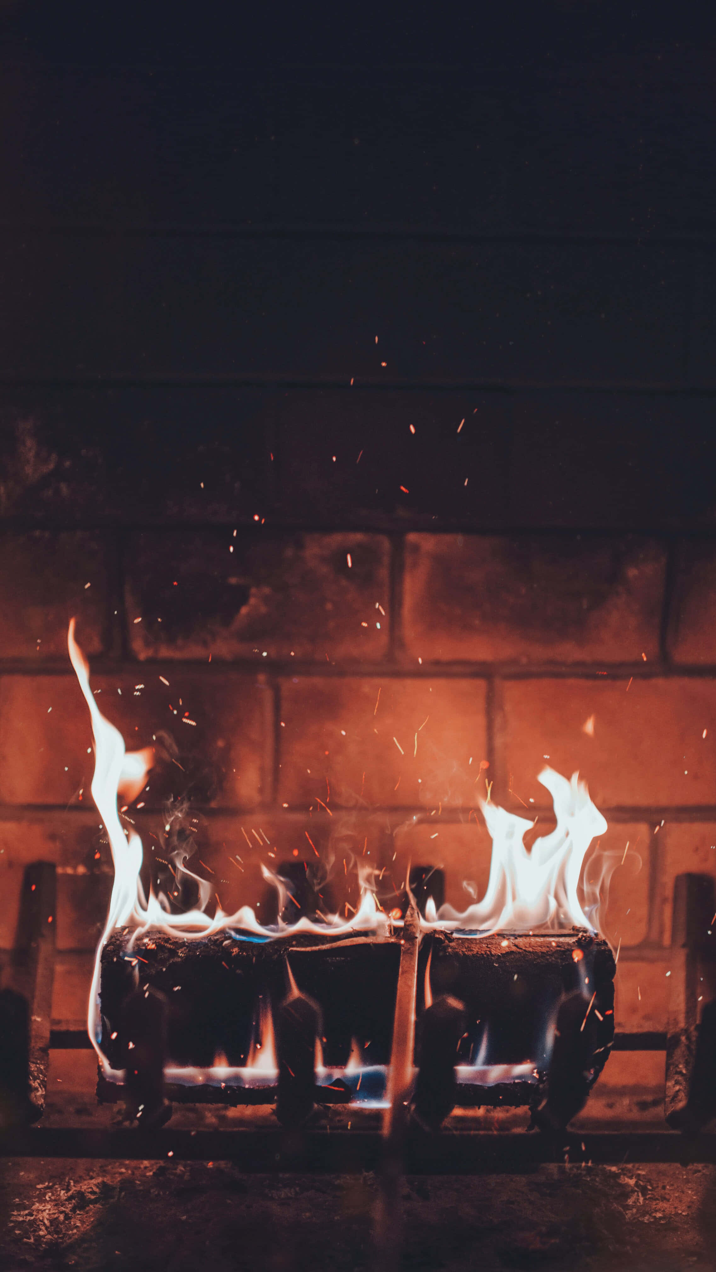 Autumn Fireplace 桌布 壁紙 — 鮮豔的橙色和藍色火焰在深色磚牆前從燃氣灶爐頭中充滿活力地舞動。