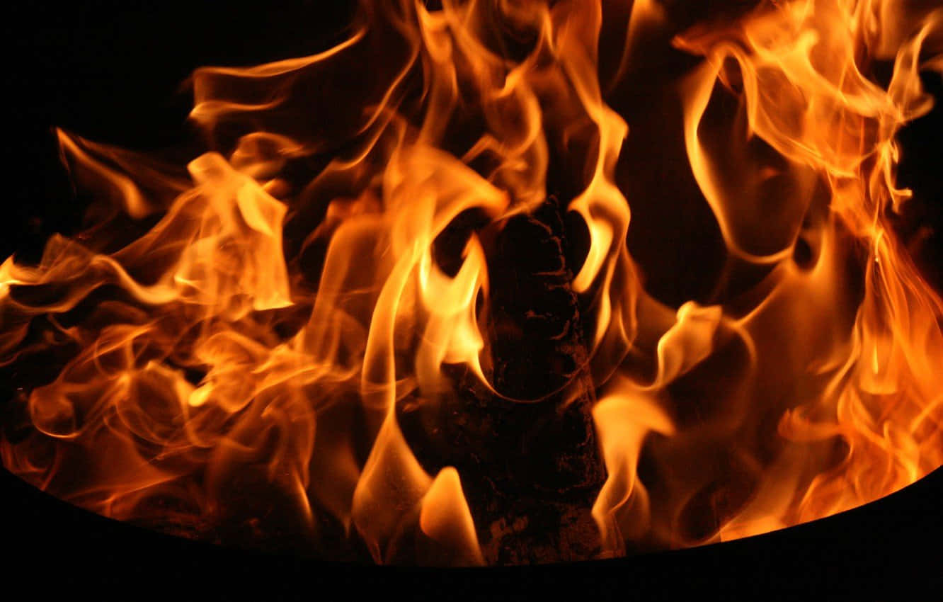 Flames 桌布 壁紙 — 鮮豔的橙色和黃色火焰在漆黑的背景下圍繞著燒焦的木頭劇烈舞動。