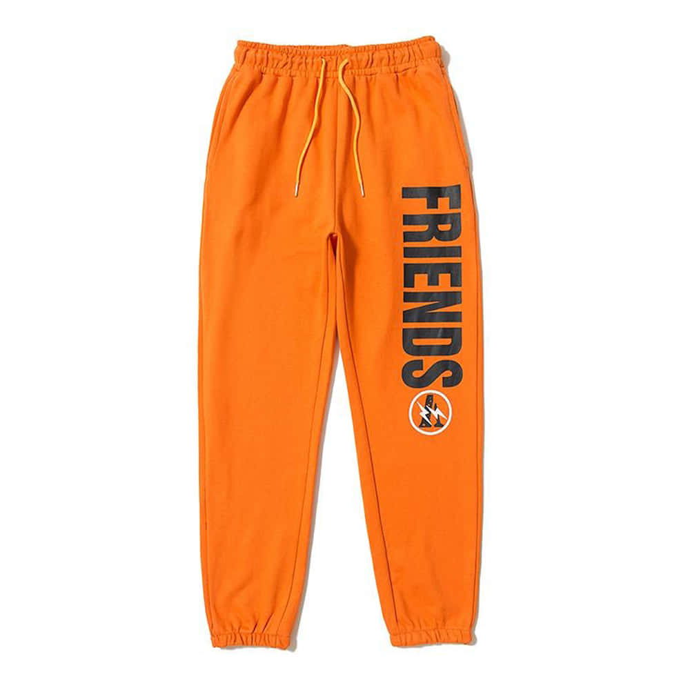 Vlone 桌布 壁紙 — 鮮豔的橙色運動褲，褲腿上帶有粗體黑色 'FRIENDS' 文字和標誌，背景為純白色。