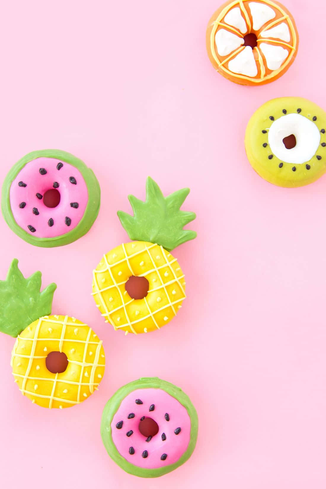 Cute Donut 桌布 壁紙 — 鮮豔的水果主題冬甩，造型為西瓜、菠蘿、奇異果和橙，排列在柔和的粉紅色背景上。