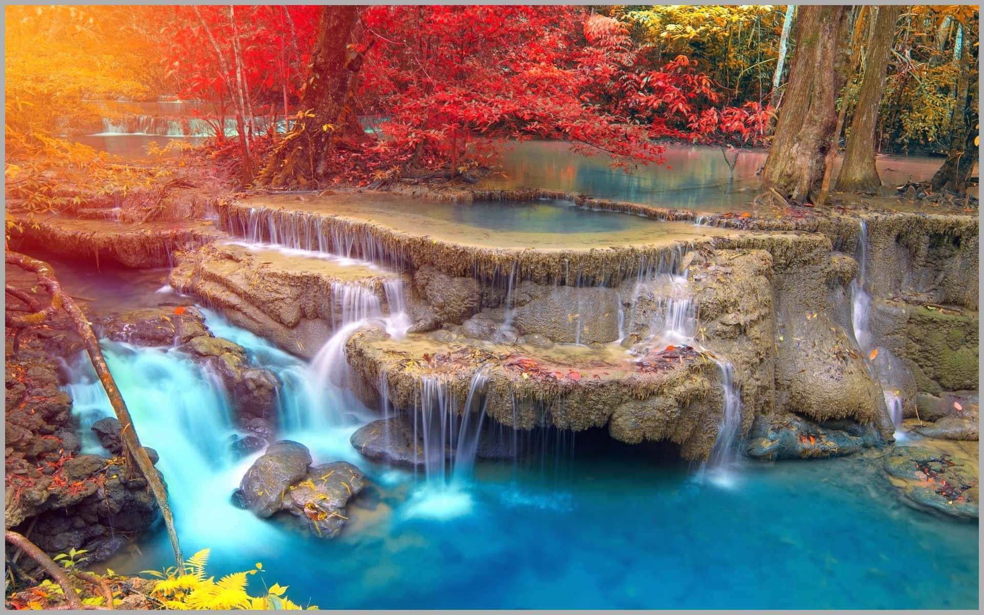 3d Waterfall 桌布 壁紙 — 鮮豔的秋葉環繞著層疊的綠松石瀑布，流過長滿苔蘚的岩石，在寧靜的森林中。