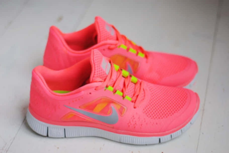 Pink Shoes 桌布 壁紙 — 鮮豔的粉紅色Nike跑鞋配螢光鞋帶，放在淺色木地板上。