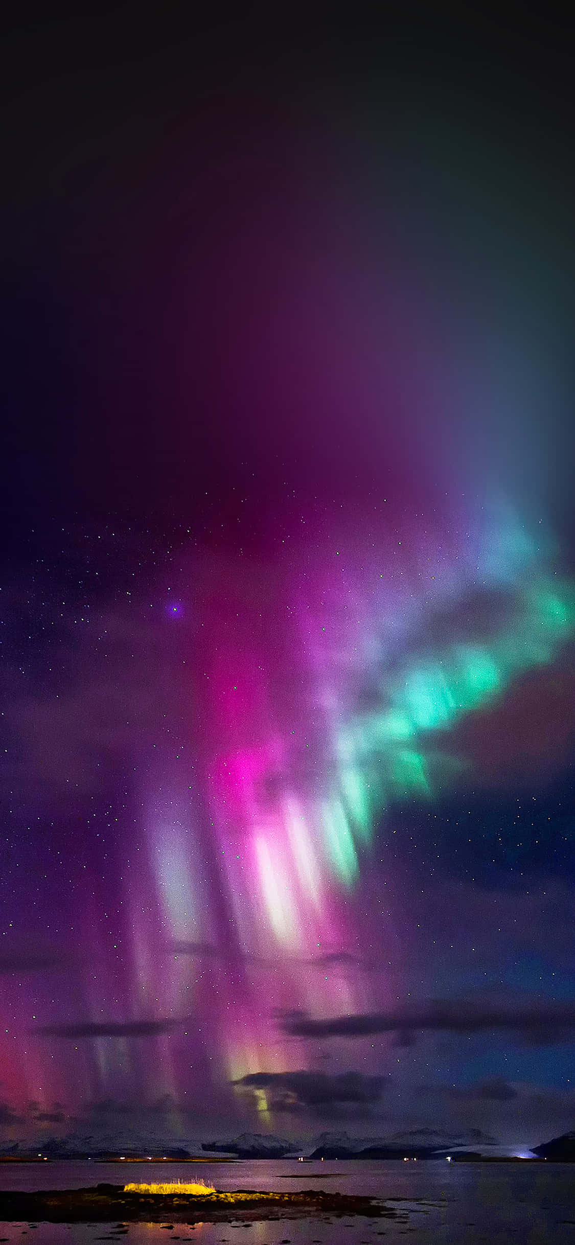 Trippy Sky 桌布 壁紙 — 鮮豔的粉紅色和綠色極光在黑暗海岸景觀上方的星空夜空中舞動。
