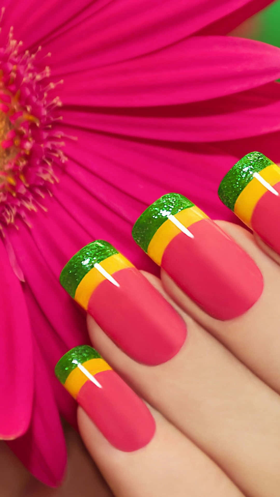 Cute Nails 桌布 壁紙 — 鮮豔的粉紅色花朵，配以展示大膽粉紅、綠色和黃色條紋指甲的手。