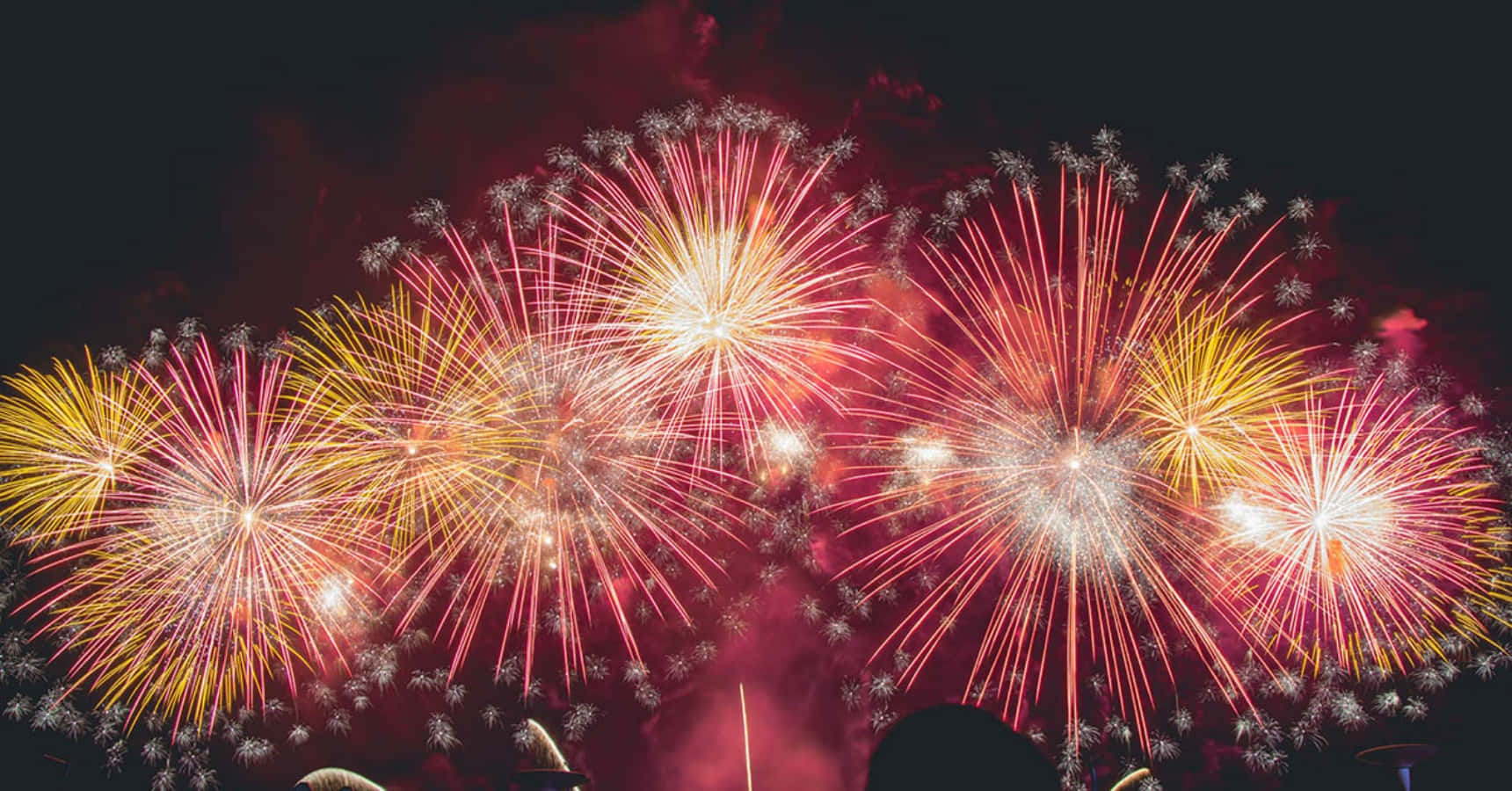 New Years Eve 桌布 壁紙 — 鮮豔的紅色、黃色和白色煙火在漆黑的夜空中綻放，呈現出耀眼奪目的景象。