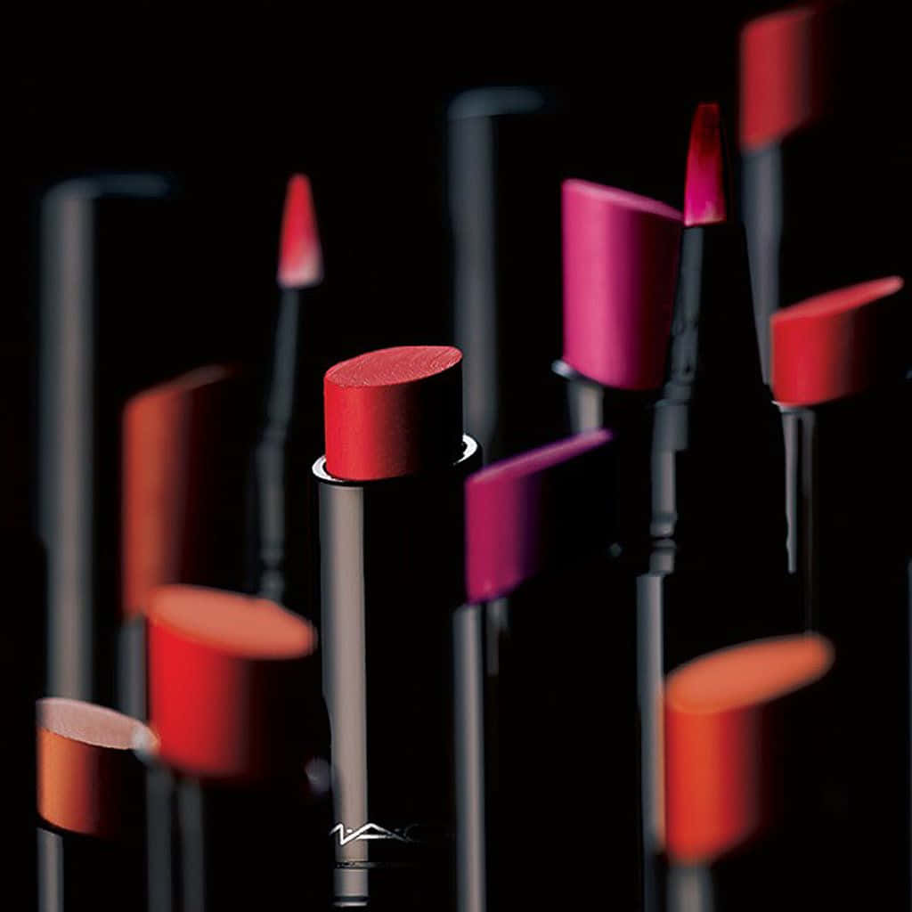 Cosmetics 桌布 壁紙 — 鮮豔的紅色和粉紅色MAC唇膏以戲劇性的特寫方式排列在黑色背景上，景深較淺。
