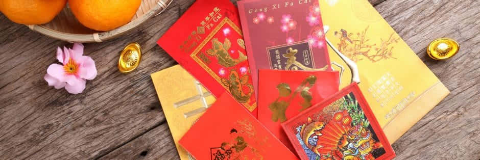 Red Envelope 桌布 壁紙 — 鮮豔的紅色和金色中國新年利是封帶有節日設計，放在質樸的木桌上，旁邊有橙子和粉紅色的櫻花。