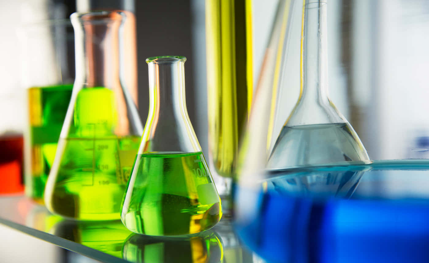 Chemistry 桌布 壁紙 — 鮮豔的綠色和藍色液體在明亮光線下，於反射實驗室架上的玻璃燒瓶中閃爍。