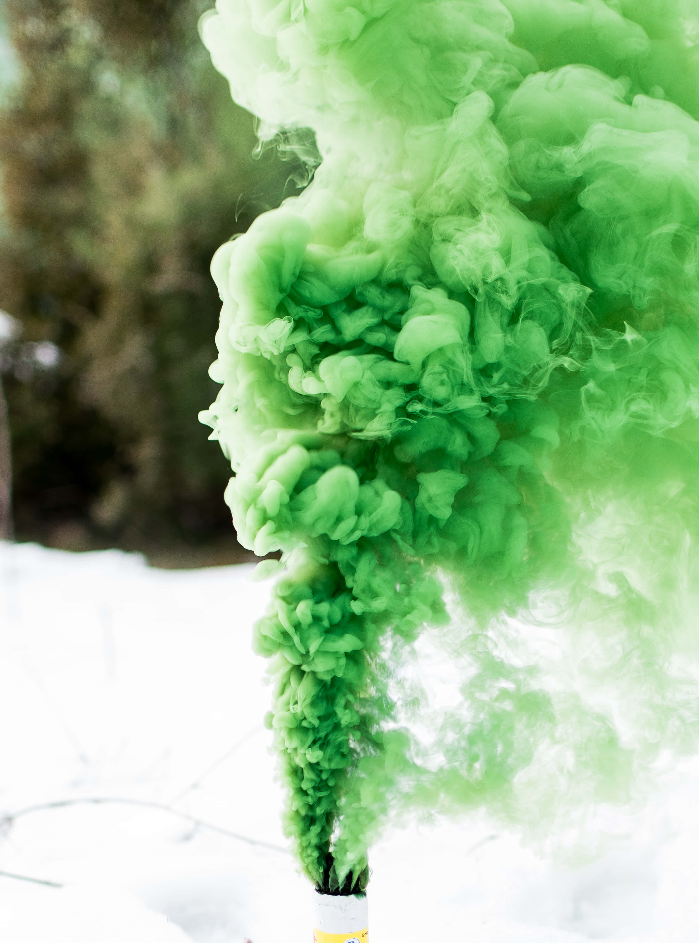 Green Smoke 桌布 壁紙 — 鮮豔的綠色煙霧在白雪皚皚的冬季背景和模糊的樹木襯托下戲劇性地翻騰。